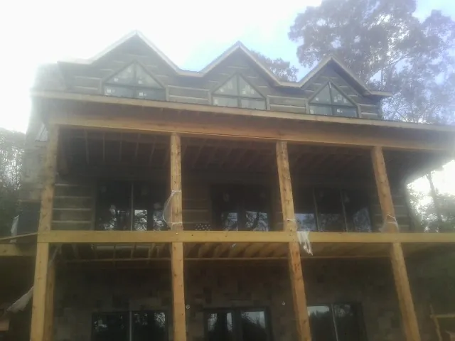 Dormers and porch framing on a large log home under construction — Roof Coating work by our crew in Duluth