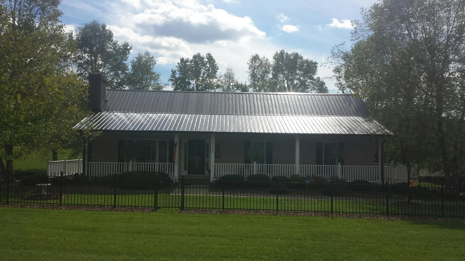 Gray metal roof on a brick ranch with a full width front porch — Gutter Guard Installation work by our crew in Duluth